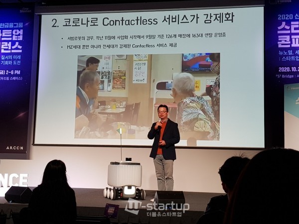 우아한형제의 배달로봇이 실제 생수를 전달하는 포퍼먼스를 보인후 김요섭 로봇사업실 총괄의 연설에서 대기하고 있다.