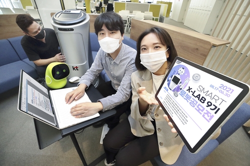KT 직원들이 로봇 우수기업 선발 공모전 포스터를 확인하고 있다. /사진=KT