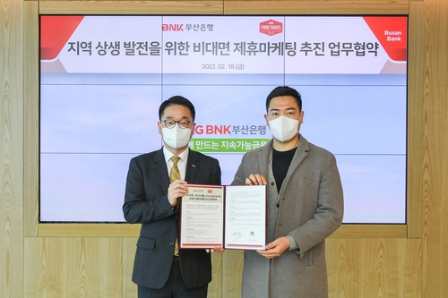 BNK부산은행은 지난 18일 BNK핀테크랩 3기 수료 기업인 푸드트래블과 ‘지역 상생 발전을 위한 업무협약’을 체결했다. 김양욱 BNK부산은행 언택트영업부장(왼쪽)과 박상화 푸드트래블 대표가 기념촬영을 하고 있다./사진=BNK부산은행 제공