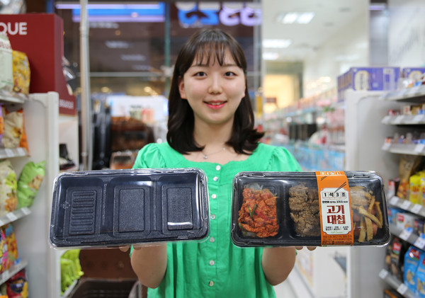 모델이 탄소 배출량 25%를 절감한 발포용기와 해당 용기를 사용한 간편식을 들고 포즈를 취하고 있다/사진=GS25
