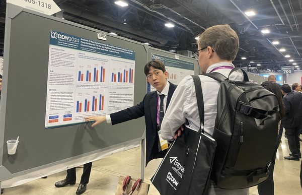 문석용 대웅제약 임상연구팀원(왼쪽)이 해외 의료진에 펙수클루의 주증상 완화율 관련 포스터를 소개하고 있다/사진=대웅제약
