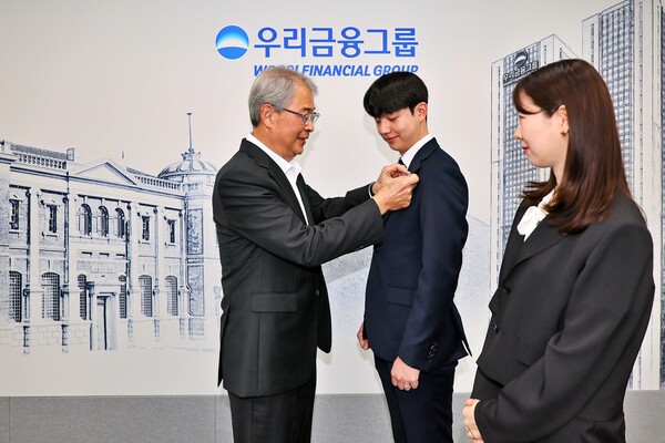 우리금융그룹 임종룡 회장이 그룹의 새 가족이 된 동양생명·ABL생명 직원에게 디지털 선도의 의미가 담긴 새로운 그룹 보조휘장을 달아주고 있다. /사진=우리금융그룹