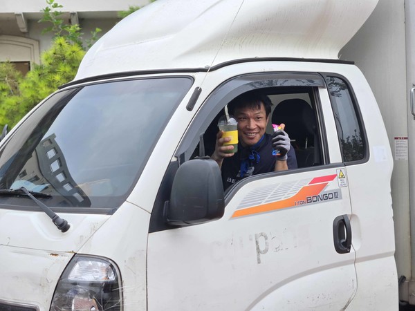 31일, 폭염 속에 쿠팡 일산 캠프 소속의 한 퀵플렉서가 쿠팡 파트너스 연합회(CPA)가 제공한 시원한  음료와 간식을 들고 응원의 마음에 화답하고 있다./사진=쿠팡 파트너스 연합회(CPA) 제공